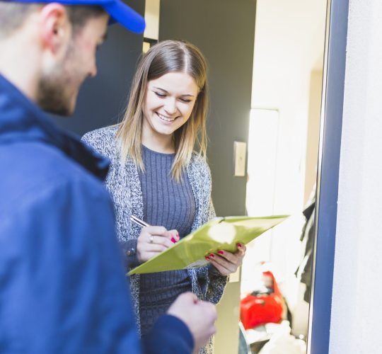 cheerful-woman-signing-paper-after-delivery